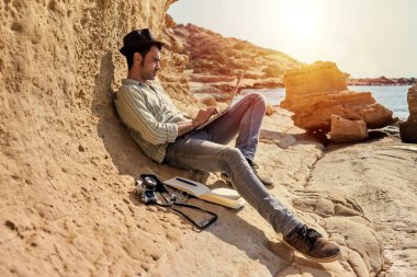 Genç bir gazeteci gün batımında plajdan uzaklaştığında rahatlıyor. Yanında fotoğraf makinesi, not defteri ve akıllı telefonu var..