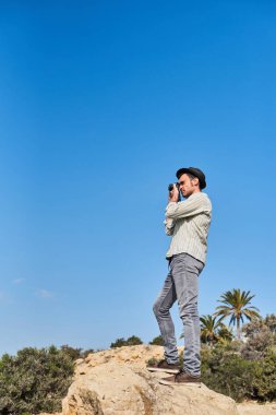 Bir hippi turist tatildeyken şapka, gömlek ve kot pantolon giyer..