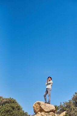 Bir hippi turist tatildeyken şapka, gömlek ve kot pantolon giyer..