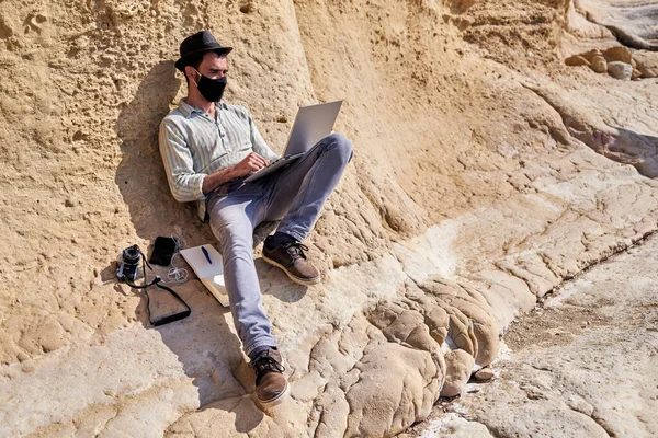 Young Hipster Hat Uses His Laptop Rocky Beach Next Him — Stock Photo, Image