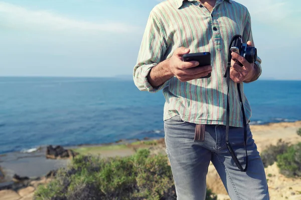 Unrecognizable Traveler Man Uses Smartphone While Holding Vintage Camera Sea — Stock Photo, Image