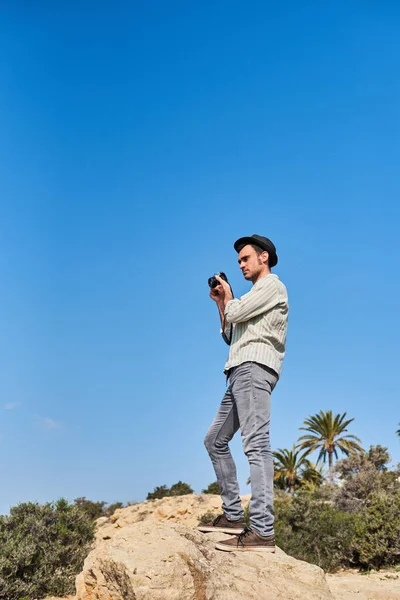 Hipster Tourist Uses Vintage Camera While Vacation Wearing Hat Shirt — Stock Photo, Image