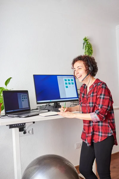 Woman Working Remotely Standing Wearing Headset Taking Notes Her Pad — Stock Photo, Image