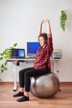 Kadın, çalışma masasının önündeki bir spor salonunda çalışırken esniyor.