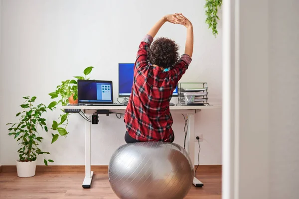 Kadın, çalışma masasının önündeki bir spor salonunda çalışırken esniyor.
