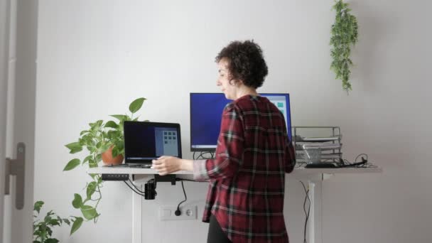 O femeie din spate lucrează la un birou reglabil la înălțime — Videoclip de stoc