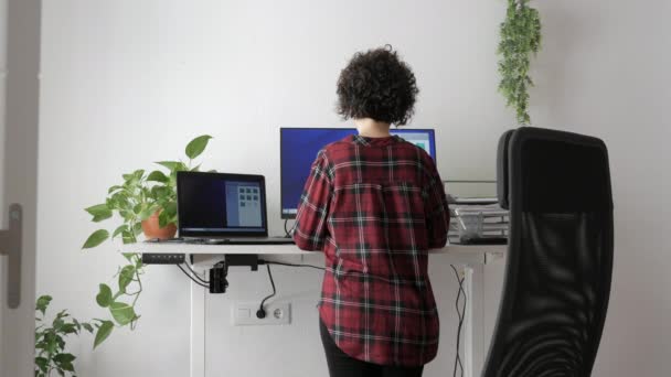 Una mujer de atrás trabajando en un escritorio ajustable en altura — Vídeos de Stock