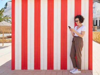 Yaz tatili boyunca telefona bakan bir kadın.