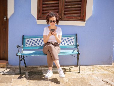 Çok renkli bir köyde akıllı telefonunu kullanan bir kadın.