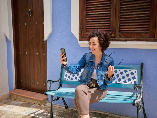 Caucasian woman taking a selfie sitting on a bench — Stock Photo, Image