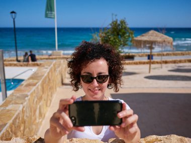 Plaj kulübesinin yanında selfie çeken bir kadın.