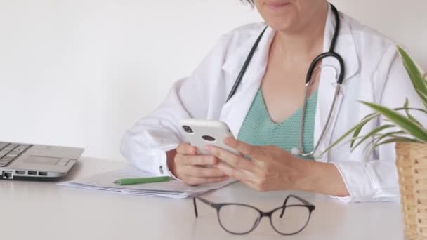Неузнаваемая женщина-врач обслуживает пациента по телефону в своем кабинете — стоковое видео