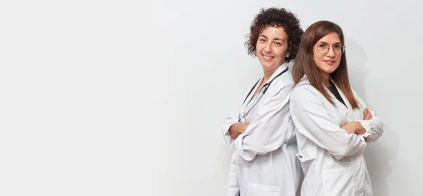 Portrait of two female doctors back to back looking at camera — Stock Photo, Image