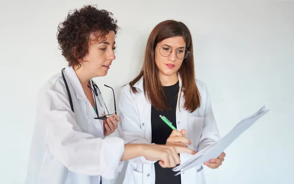 İki kadın doktor belgelere bakar ve teşhisi tartışır.