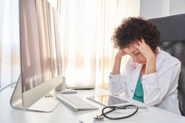 Bir kadın doktor dijital tabletine odaklanmış görünüyor.