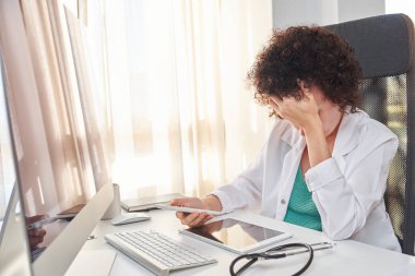 Kadın bir doktor hayal kırıklığının bir işareti olarak ellerini yüzüne koyar.