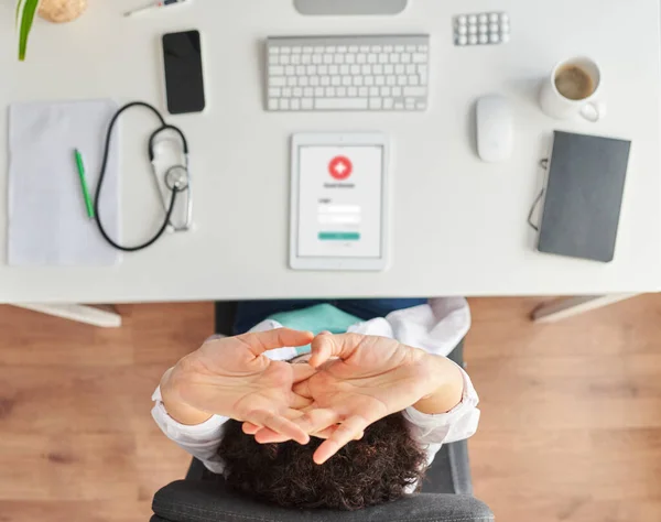 Top view of a female doctor stretching sitting at the desk in her medical office — Stock Photo, Image