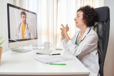 İş arkadaşıyla görüntülü görüşme yapan kadın doktor.