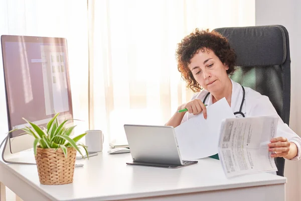 Kadın doktor, ofisindeki tabletle belgeleri dijital ortama aktarıyor.