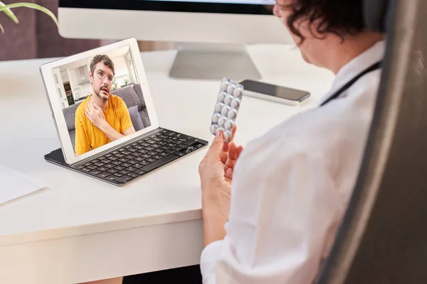 Kobieta lekarz przepisuje tabletki pacjentowi poprzez konsultację internetową. — Zdjęcie stockowe