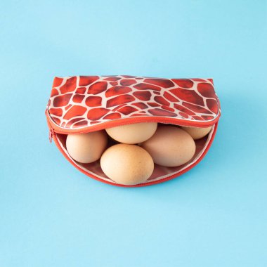 Dişi bir çantada yumurta. Parlak mavi arkaplanda Paskalya Sıralaması.