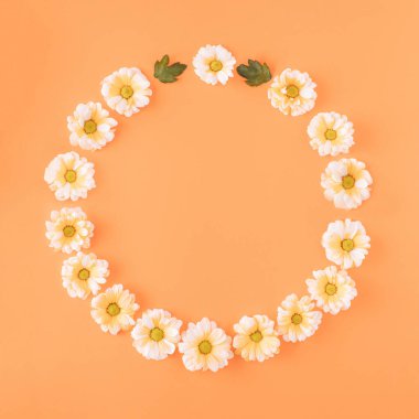 Beyaz Margarita çiçeklerinden yapılmış, içinde mesaj olan bir daire. Turuncu arka planda çok az çiçek konsepti