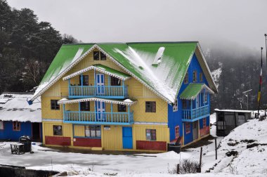 Parlak görünümlü, parlak mavi, yeşil, karla kaplı bir kulübe.