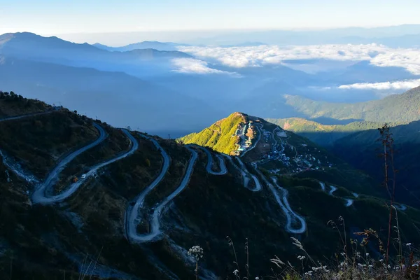 Dağ zirvesi sabahın erken saatlerinde altın güneş ışığıyla yıkandı, yamaçta yılan otobanı var.