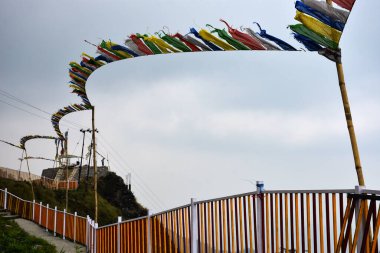 Sarı ve beyaz demir parmaklıklar ve dalgalı dua bayrakları.