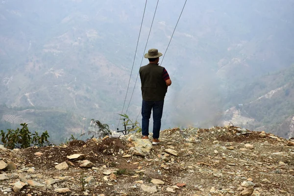 一个头戴帽子站在山顶上俯瞰山谷的男人 — 图库照片