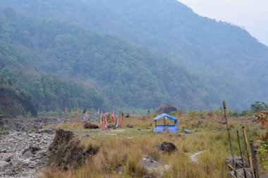 Levees nehrinin tepesinde yeşil ve kahverengi bitkilerle kaplı, kayalar dua bayrakları. Ben...