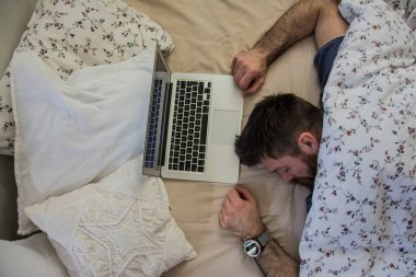 Dizüstü bilgisayarı olan genç adam evde çalışıyor.