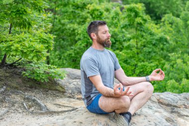 Genç adam dışarıda yoga yapıyor.