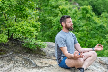 Genç adam dışarıda yoga yapıyor.