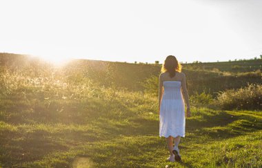 Beyaz elbise arkadan, gün batımında kadın açık havada.