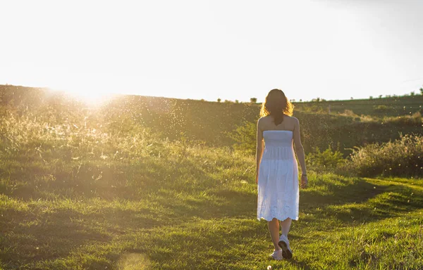 Beyaz elbise arkadan, gün batımında kadın açık havada.