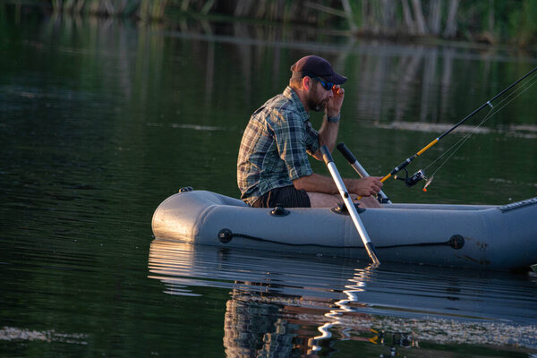Mature man fishing on the lake from inflatable boat