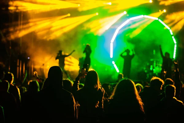 crowd at concert and silhouettes in stage lights .silhouettes of concert crowd in front of bright stage lights .cheering crowd in front of bright stage lights . blured lights