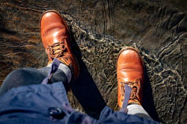 Yürüyüş gezisindeki Vasky ayakkabıları. Güneşli bir günde nehirden geçmek.