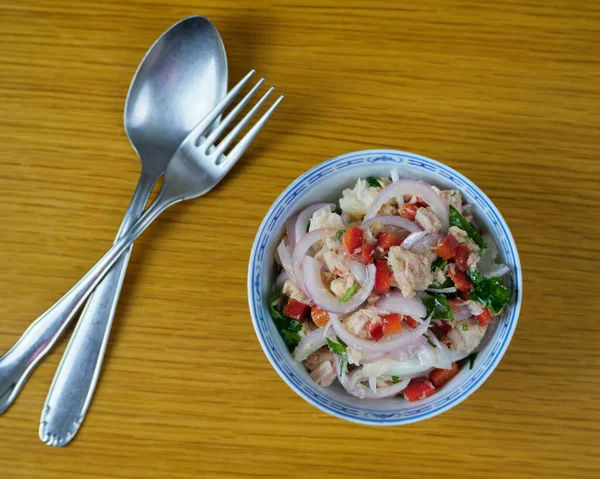 Peruvian hake and tune ceviche with vegetables, spices and lime in a ceramic bowl with cutlery. Top View