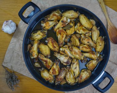 Sarımsaklı Tavuk Kanatları (Pollo al ajillo). İspanyol Tapa tabağı, içindeki malzemelerle süslenmiş bir peçetenin üzerinde kızartma tavasında. Üst Görünüm