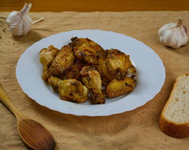 Sarımsaklı Tavuk Kanatları (Pollo al ajillo). İspanyol Tapa tabağı, kabuklu ekmek ve malzemeleriyle kahverengi bir peçeteye servis edilir..