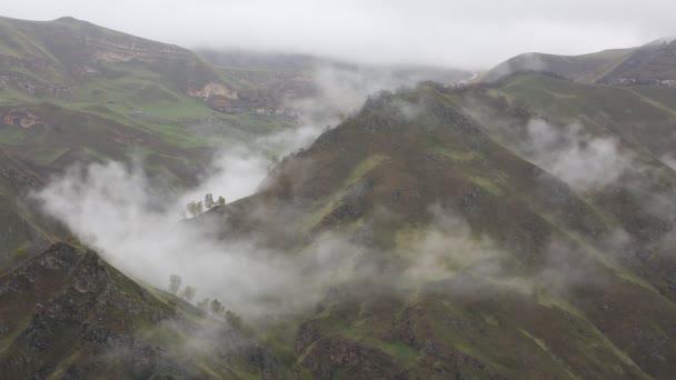 Russia. All'inizio della primavera il fitto velo di nebbia e nuvole striscia sui ripidi pendii montani delle cime del Caucaso centrale . — Video Stock