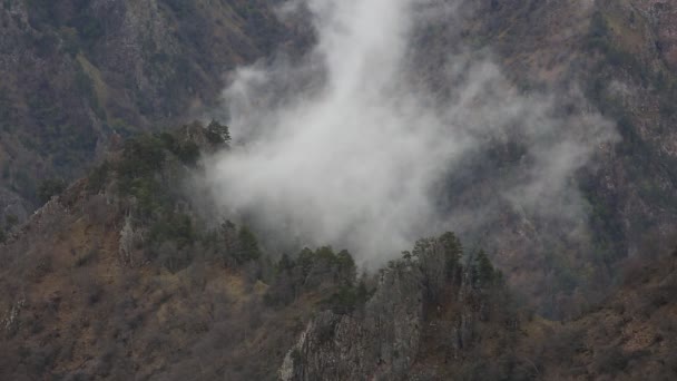 Russia. In early spring the dense veil of mist and clouds creeping up the steep mountain slopes of the Central Caucasus peaks. — Stock Video