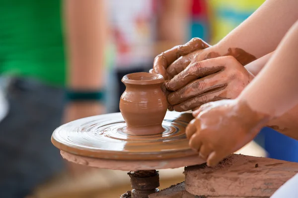 El üstünde a tekerlek seramik sürahi çocuk ha yapmak için yardım