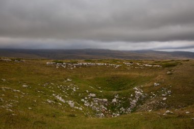 Gri sonbahar gökyüzü ve dağlar sararmış çimenlerin üzerinde.