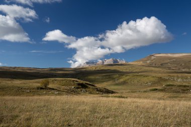 Sonbahar mavi gökyüzü beyaz bulutlar ve dağ üzerinde sararmış 