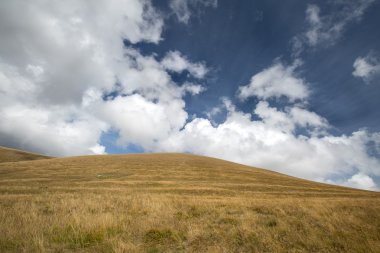 Sonbahar mavi gökyüzü beyaz bulutlar ve dağ üzerinde sararmış 