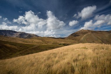 Sonbahar mavi gökyüzü beyaz bulutlar ve dağ üzerinde sararmış 