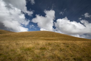 Sonbahar mavi gökyüzü beyaz bulutlar ve dağ üzerinde sararmış 